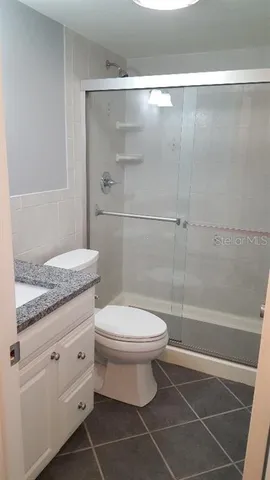 a bathroom with a granite countertop toilet a sink and a shower