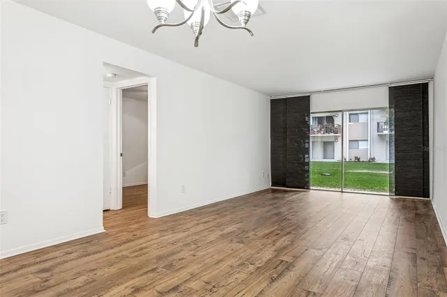 a view of an empty room with a window and wooden floor
