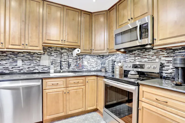 a kitchen with stainless steel appliances granite countertop white cabinets sink and a microwave