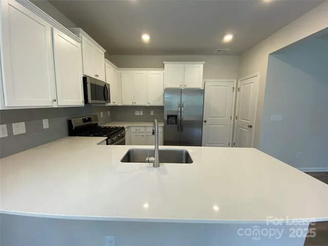a kitchen with stainless steel appliances a refrigerator sink microwave and cabinets