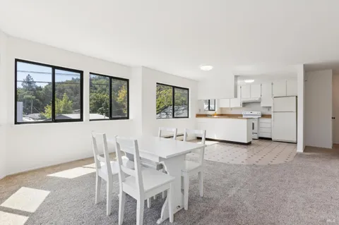 a kitchen with a dining table chairs and large window