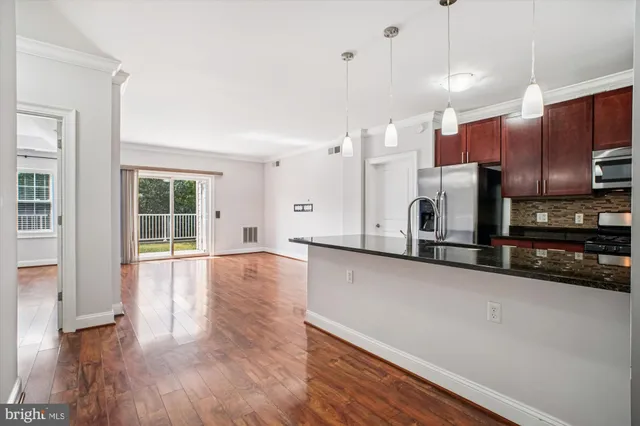 a view of a kitchen with stainless steel appliances wooden floor and a window