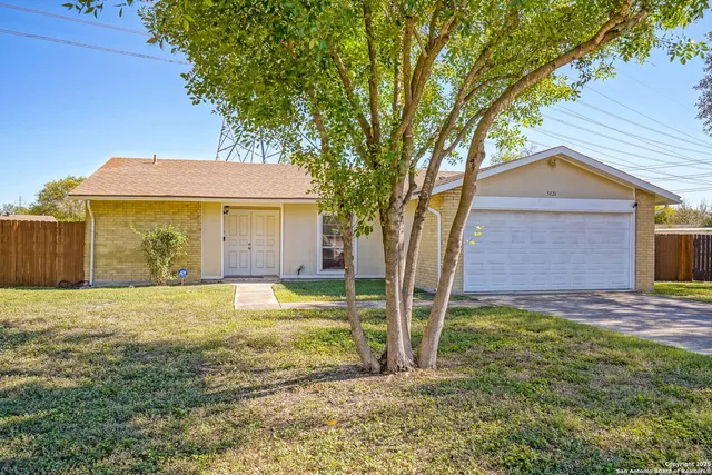 a view of a house with a yard and large tree