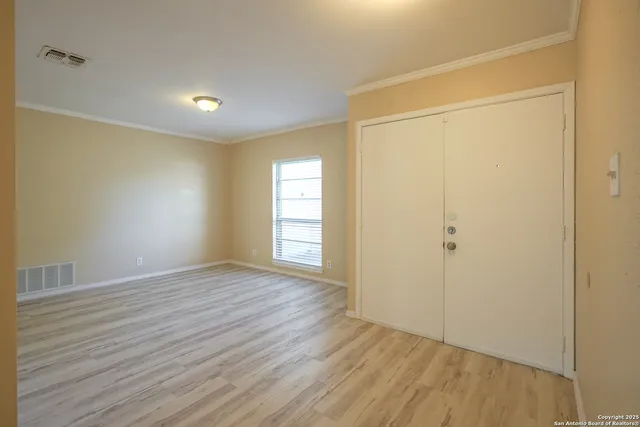a view of an empty room with wooden floor and closet