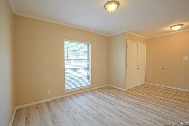 an empty room with wooden floor a ceiling fan a fireplace and windows