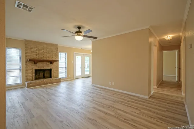 a view of an empty room with wooden floor fireplace and a window