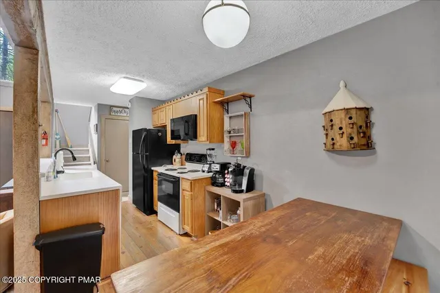 a kitchen with stainless steel appliances granite countertop a stove a sink dishwasher and a refrigerator with wooden floor