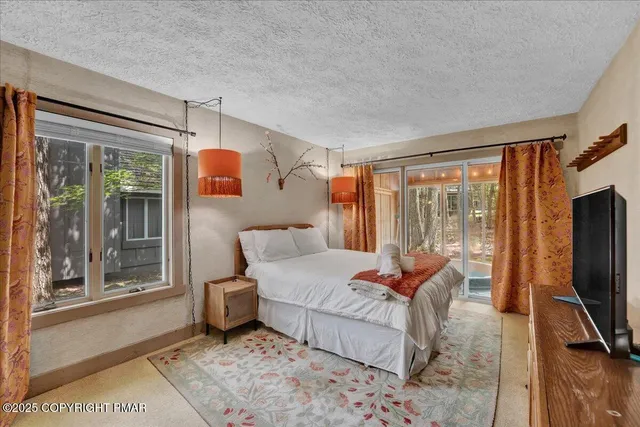 a bedroom with a bed and large windows