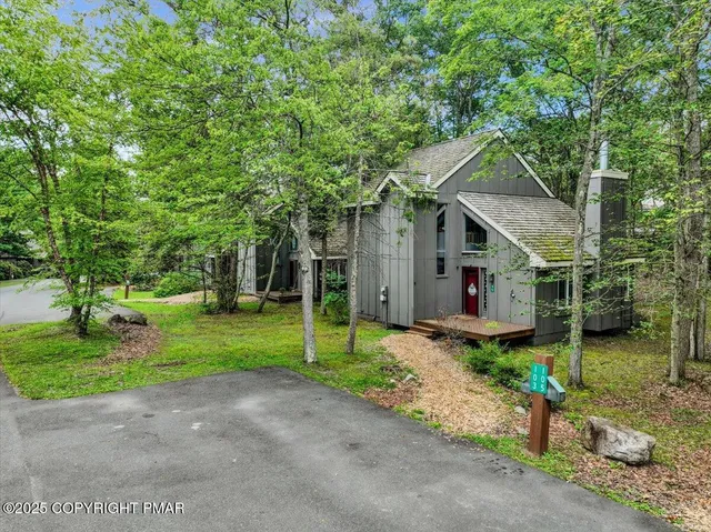 a front view of house with small garden and tree