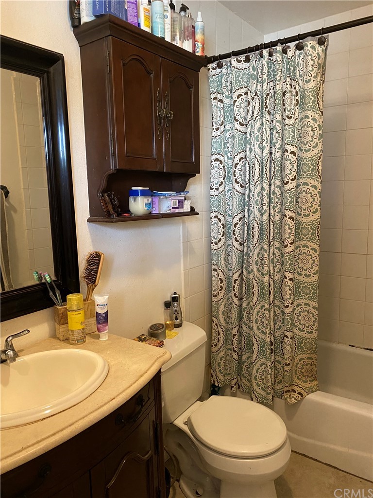 4684 Olive Street Montclair, CA 91763 - Photo 9 of 13 a bathroom with a sink a toilet and shower curtain