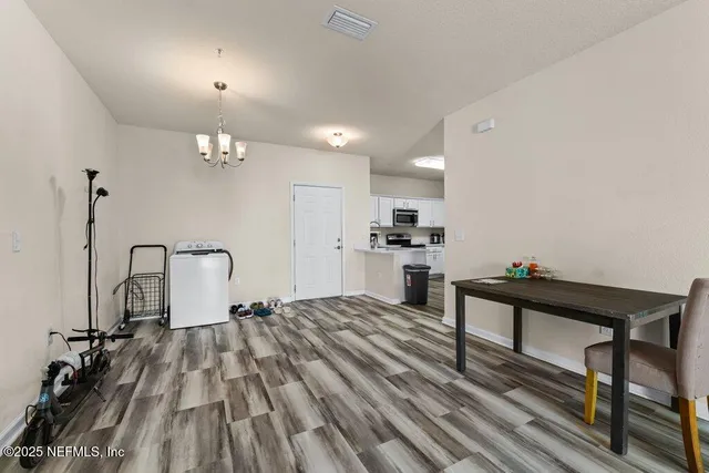 a view of a room with kitchen island stainless steel appliances wooden floor dining table and chair