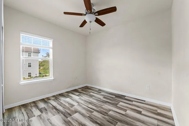 an empty room with a window and a ceiling fan