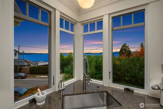 a view of a brick house with a floor to ceiling window and potted plants