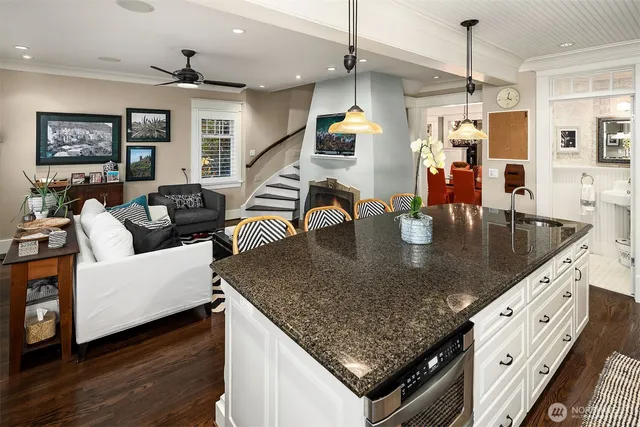 a kitchen with stainless steel appliances granite countertop a sink dishwasher and a dining table with wooden floor