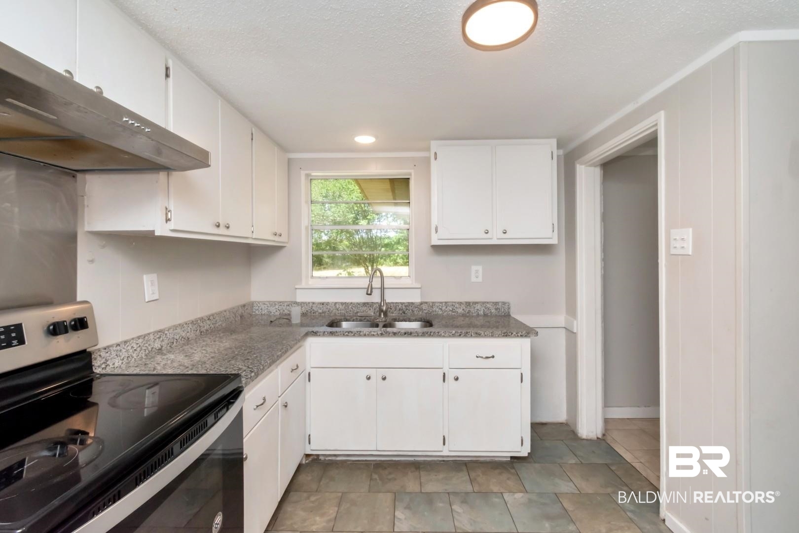 5650 Alice Drive Theodore, AL 36582 - Photo 8 of 15 Kitchen with a sink, under cabinet range hood, white cabinetry, and electric stove