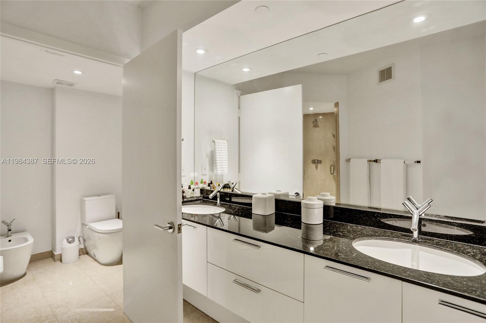 400 Alton Road, Unit 911 Miami Beach, FL 33139 - Photo 24 of 47 a bathroom with a double vanity sink toilet and a mirror