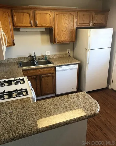 a kitchen with granite countertop a sink a stove and refrigerator