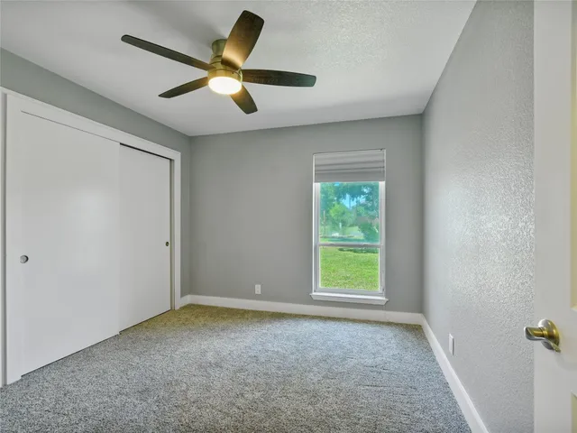 a view of a livingroom with a ceiling fan & windows