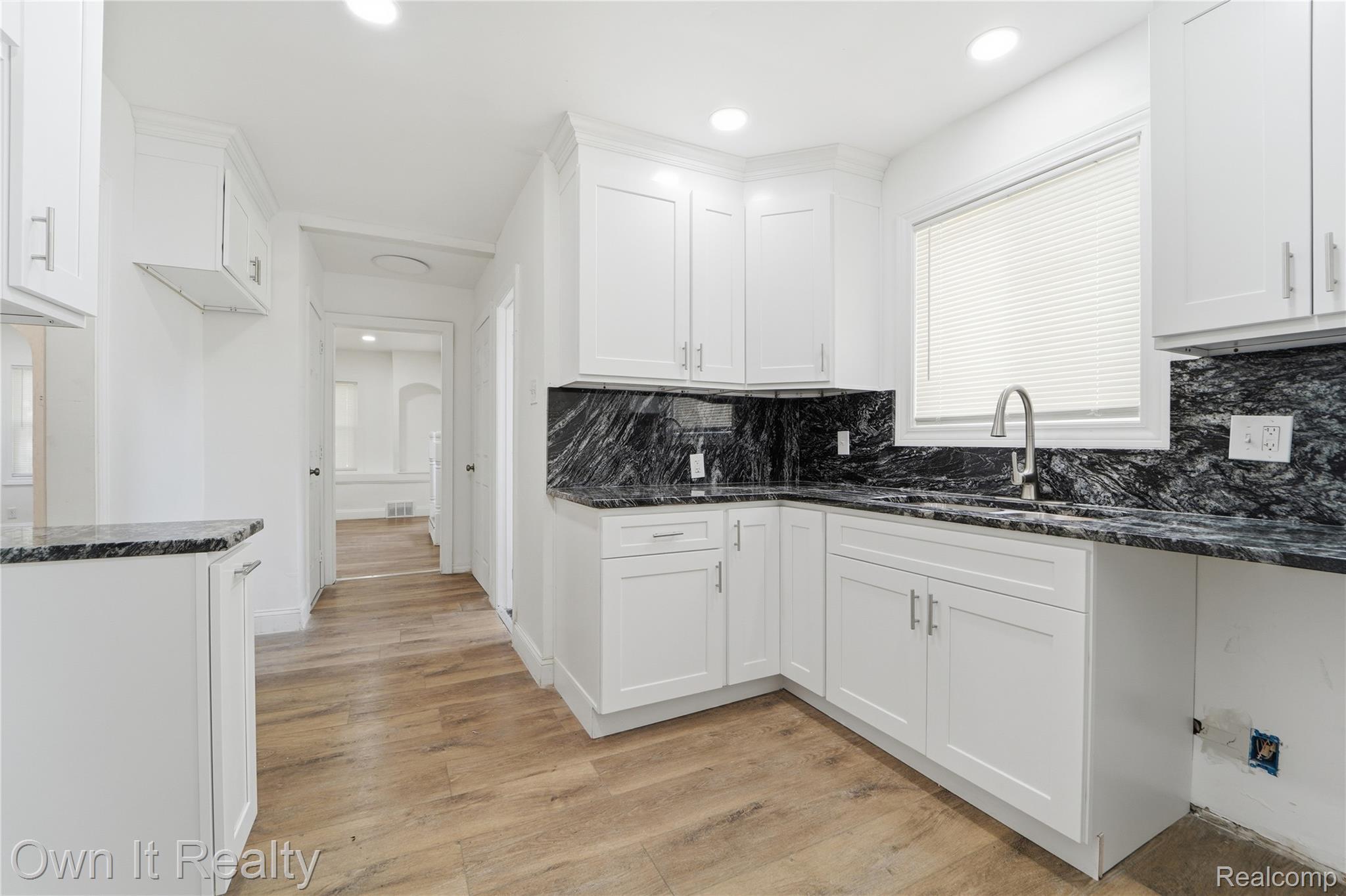 17351 Appoline Street Detroit, MI 48235 - Photo 10 of 34 Kitchen featuring wood-finish flooring, white cabinetry with silver hardware, dark patterned countertops, a stainless steel sink with a gooseneck faucet, and recessed lighting