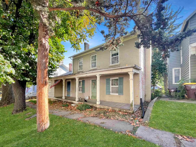 a view of a yard in front of a house with a large tree