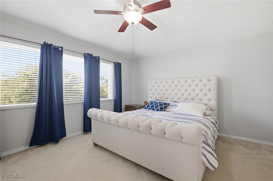 13160 Broadhurst Loop, Unit 101 Fort Myers, FL 33919 - Photo 20 of 39 a bedroom with a large bed and a chandelier fan