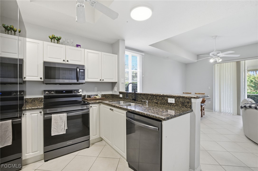 13160 Broadhurst Loop, Unit 101 Fort Myers, FL 33919 - Photo 10 of 39 a kitchen with granite countertop a stove top oven microwave and cabinets