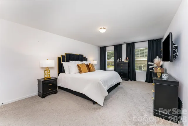 a bedroom with a large bed and a flat tv screen on dresser