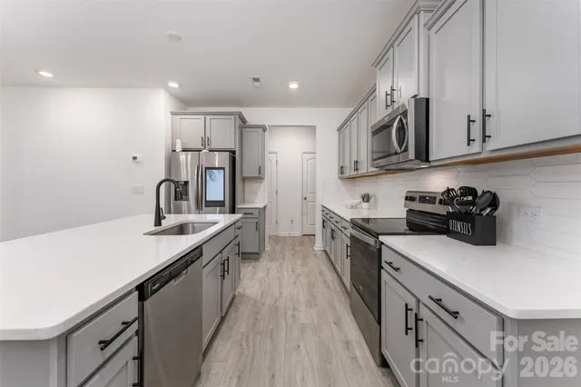 a kitchen with stainless steel appliances granite countertop a sink a stove and a refrigerator