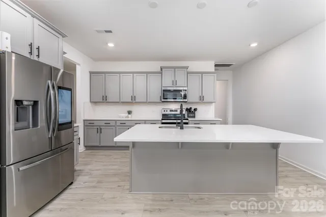 a kitchen with kitchen island a sink a stove a refrigerator and cabinets