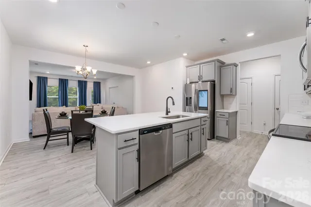 a kitchen with stainless steel appliances a stove top oven a sink dishwasher and a refrigerator