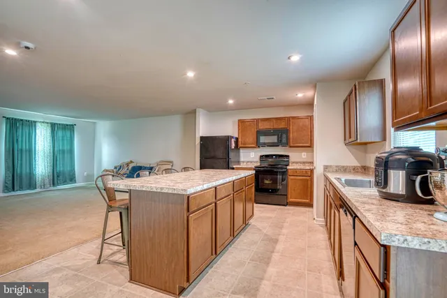 a kitchen with granite countertop kitchen island stainless steel appliances a sink stove and refrigerator