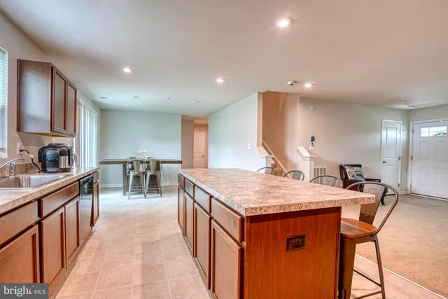 a kitchen with stainless steel appliances granite countertop a table chairs sink and cabinets