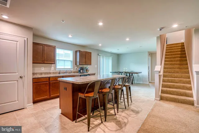 a kitchen with stainless steel appliances kitchen island granite countertop a table chairs sink and cabinets
