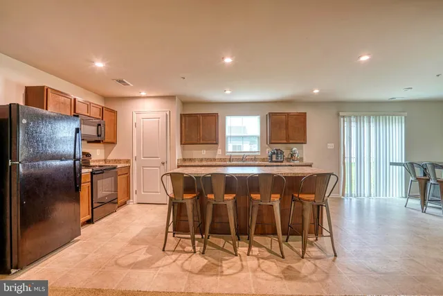 a kitchen with stainless steel appliances kitchen island granite countertop a dining table chairs and granite counter tops