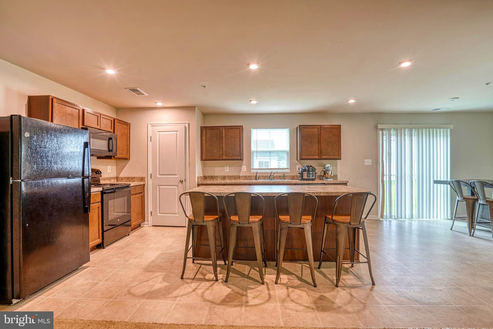 11 Saddle Bill Circle Cambridge, MD 21613 - Photo 8 of 31 a kitchen with stainless steel appliances kitchen island granite countertop a dining table chairs and granite counter tops