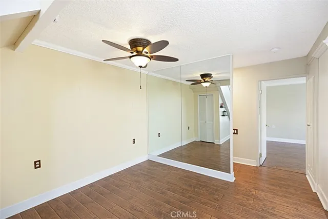 an empty room with wooden floor chandelier fan and windows