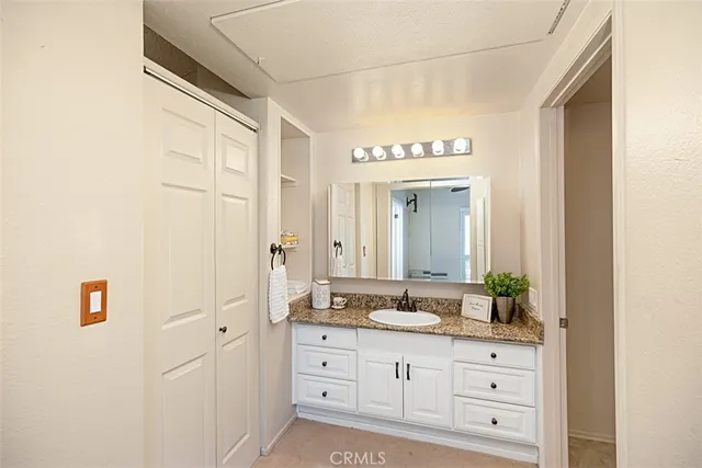 a bathroom with a granite countertop double vanity sink mirror and toilet