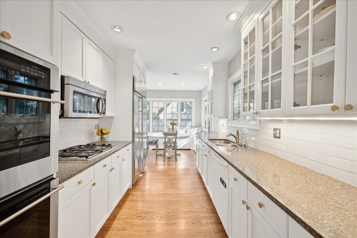 305 Poplar Street Winnetka, IL 60093 - Photo 9 of 26 a large white kitchen with stainless steel appliances granite countertop a lot of counter space and wooden floors