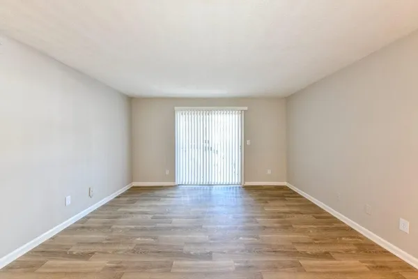 a view of an empty room with wooden floor and window
