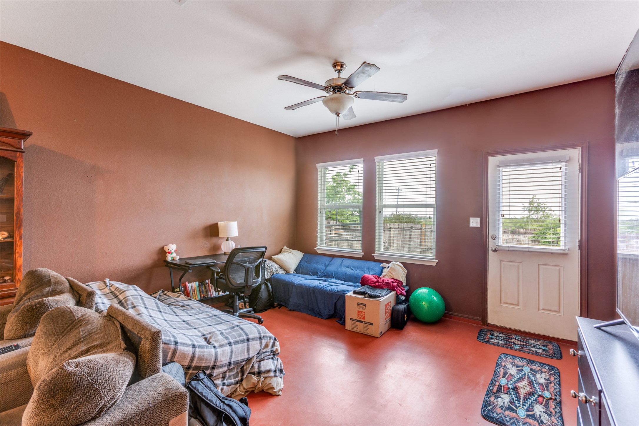 13909 Sherri Berry Way Manor, TX 78653 - Photo 14 of 28 Spacious room featuring a ceiling fan, three windows with blinds, a white exterior door with blinds, and rich terracotta-toned flooring