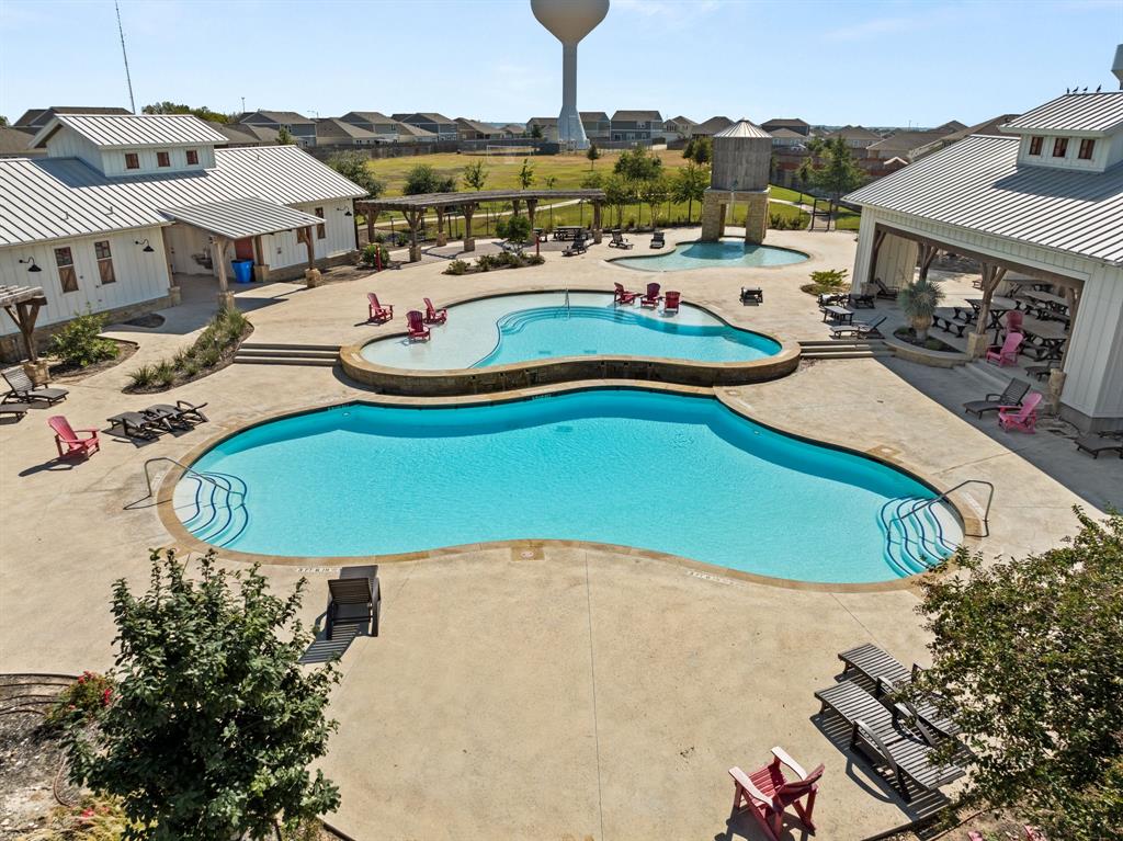 13909 Sherri Berry Way Manor, TX 78653 - Photo 24 of 28 Resort-style pool area featuring two distinct pool sections, a water feature, and extensive concrete decking
