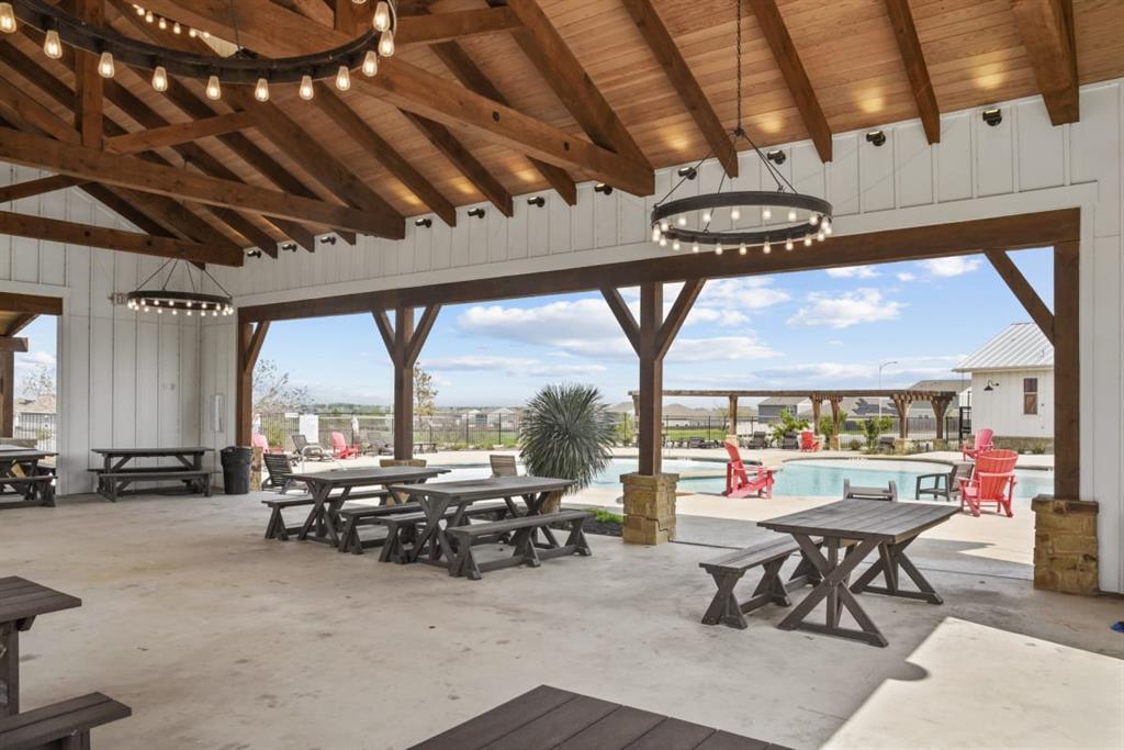 13909 Sherri Berry Way Manor, TX 78653 - Photo 26 of 28 Expansive covered patio featuring a high vaulted wood-beam ceiling, exposed rafters, and white board-and-batten siding