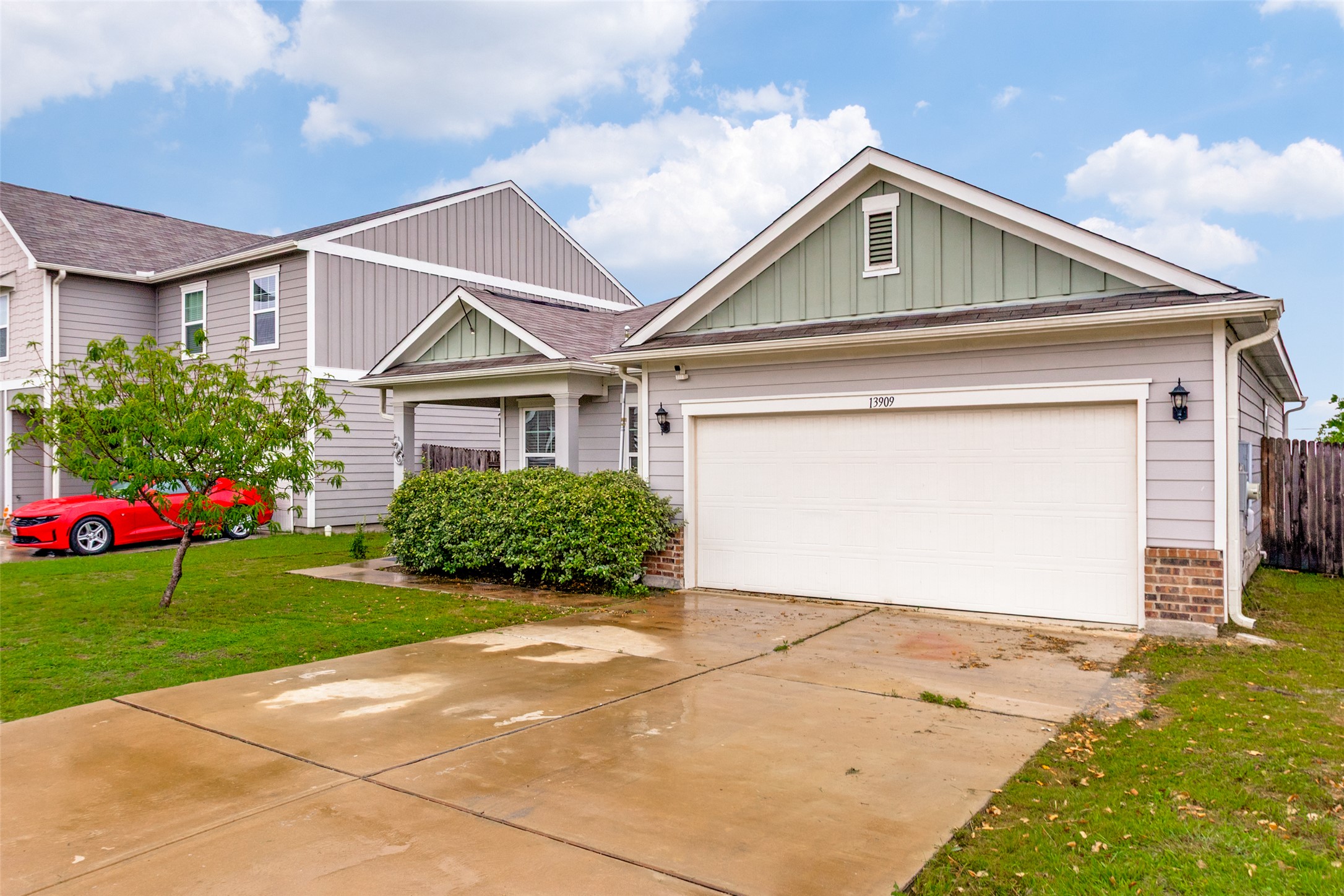 13909 Sherri Berry Way Manor, TX 78653 - Photo 28 of 28 Light gray siding exterior with a white garage door, a covered entry, and a light green gable accent