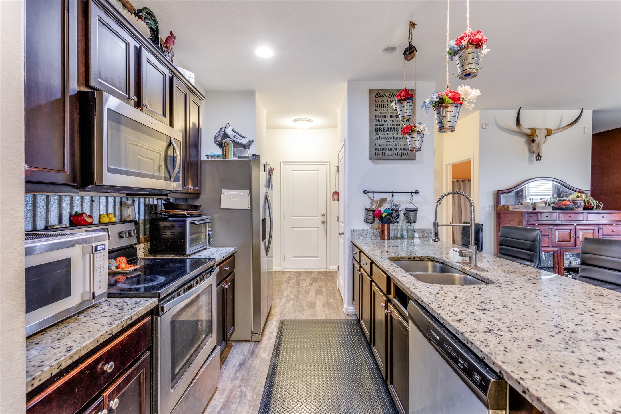 13909 Sherri Berry Way Manor, TX 78653 - Photo 3 of 28 Kitchen featuring an expansive island with a dual basin sink and a high-arc faucet, granite countertops, and stainless steel appliances