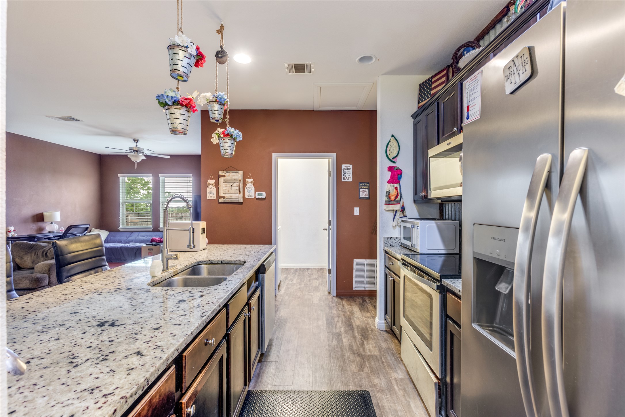 13909 Sherri Berry Way Manor, TX 78653 - Photo 5 of 28 Kitchen island featuring a dual basin sink with a gooseneck faucet, light-toned speckled countertop, and dark wood-finish cabinetry