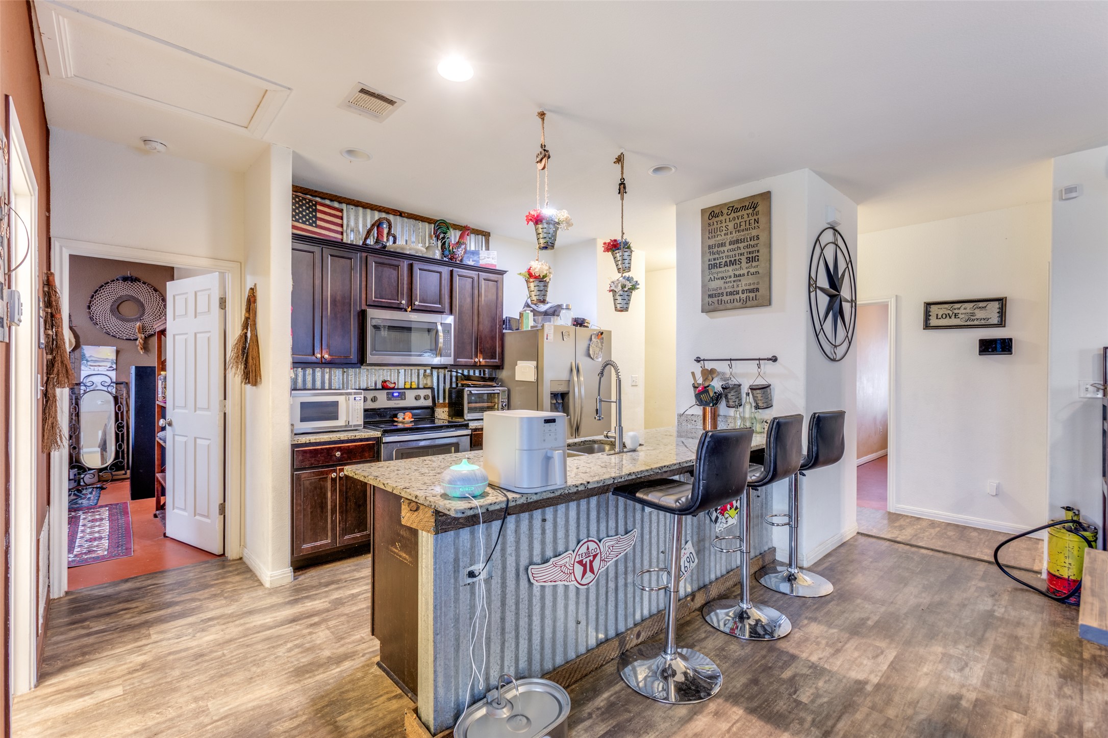13909 Sherri Berry Way Manor, TX 78653 - Photo 8 of 28 Open concept kitchen featuring an eat-at island with a granite countertop, a stainless steel sink, and dark wood cabinetry