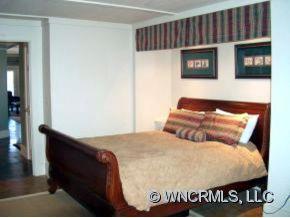 901 Hawk Ridge Drive Mill Spring, NC 28756 - Photo 11 of 12 a bed sitting in a bedroom next to a cabinet