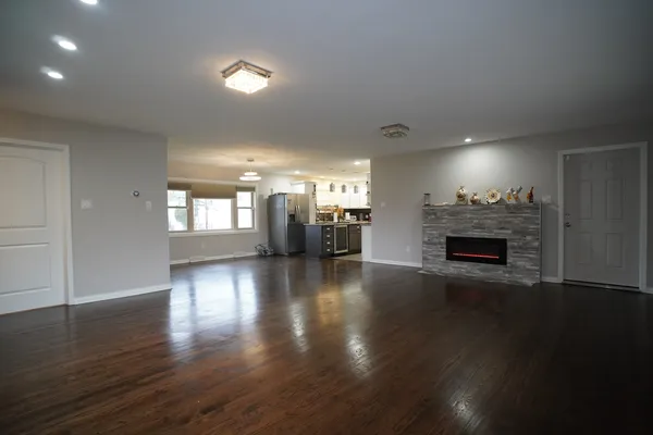 an empty room with wooden floor fireplace and windows