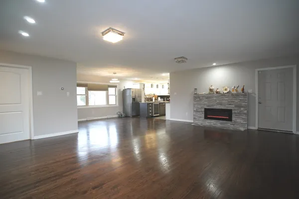 an empty room with wooden floor fireplace and windows