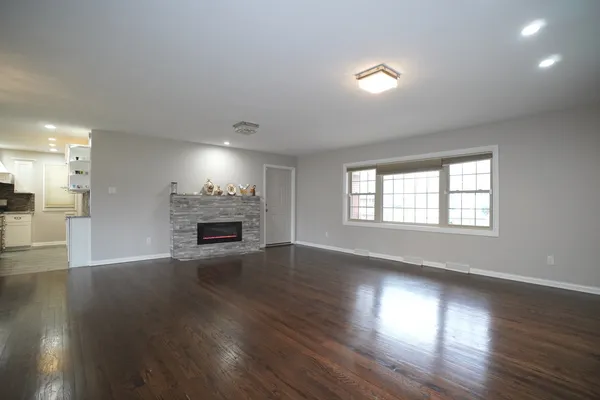 an empty room with wooden floor fireplace and windows